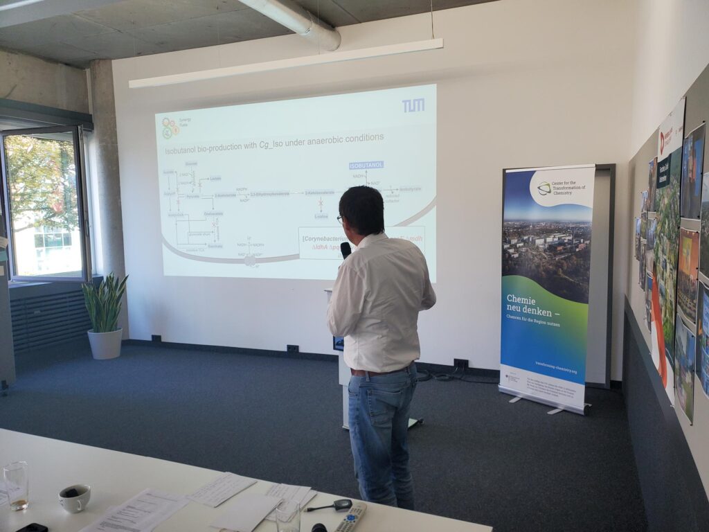 In a seminar room: The speaker stands with his back to the audience and points to his presentation. // In einem Seminarraum: Der Vortragende steht mit dem Rücken zum Publikum und zeigt auf seine Präsentation.